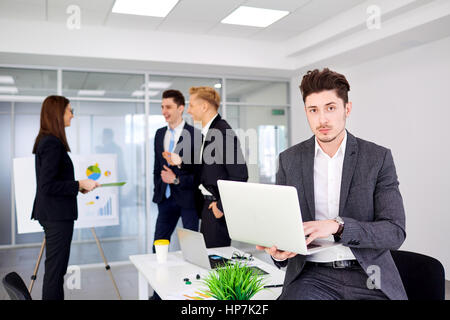 Giovane imprenditore con un laptop nelle mani di opere in backgr Foto Stock