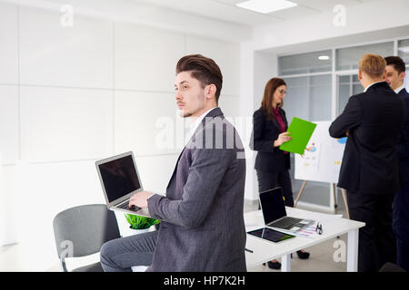 Giovane imprenditore con un laptop nelle mani di opere in backgr Foto Stock