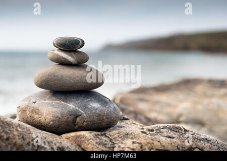 Fishguard, Galles - grandi ciottoli accatastati in un palo alto sulla spiaggia Foto Stock