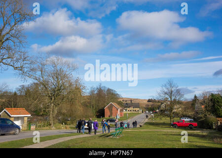 I turisti a piedi lungo il verde, la strada principale di Goathland North Yorkshire il villaggio fittizio di Aidesfield nella serie TV inverni Heartbeat di giorno Foto Stock