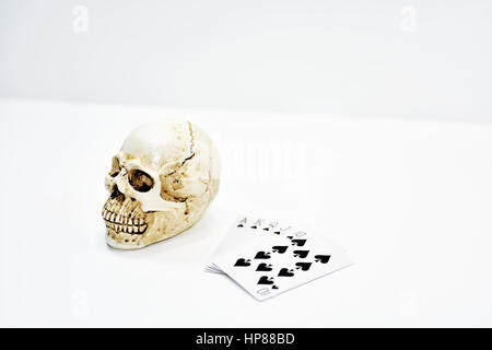 Piccolo decorativo cranio umano con le carte da gioco. Isolato su sfondo bianco. Foto Stock