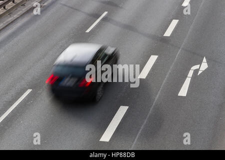 Un auto guidando lungo una strada a doppia carreggiata con una svolta a destra corsia Foto Stock