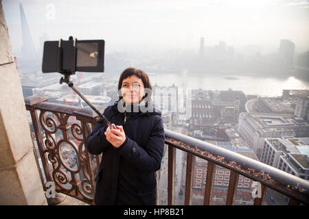 Donna prendendo un selfie dal tetto della Cattedrale di San Paolo su un nebbioso giorno a Londra, Regno Unito - city break - concetto di turismo Foto Stock