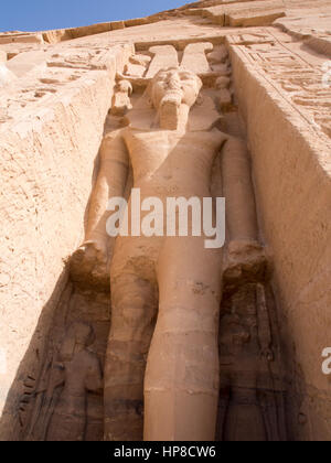 In piedi di una statua di Ramses II al di fuori del piccolo tempio in onore di Nefertari ad Abu Simbel Egitto Foto Stock