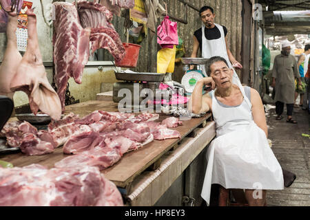 Un macellaio attende i clienti al suo stallo nella Chinatown di Kuala Lumpur in Malesia Foto Stock