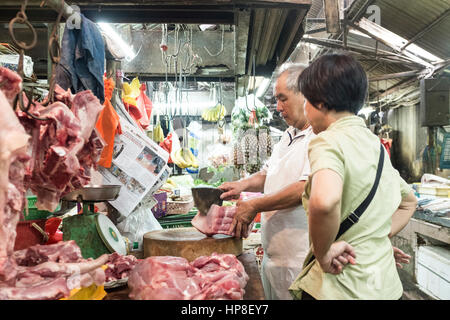 Un macellaio le costolette di carne per un cliente al suo stallo nella Chinatown di Kuala Lumpur in Malesia Foto Stock