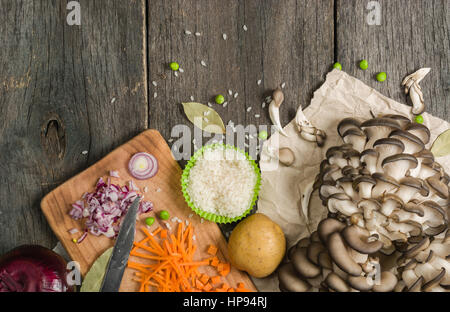 Ingredienti per la zuppa di verdure. verdure cetriolo cipolle patate carote funghi piselli spezie nella sezione sul grigio Sfondo di legno Foto Stock