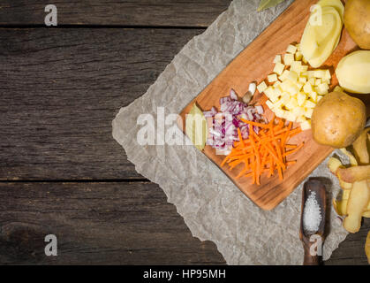 Ingredienti per la zuppa di verdure. verdure cetriolo cipolle Carote Patate piselli spezie nella sezione sul grigio Sfondo di legno Foto Stock