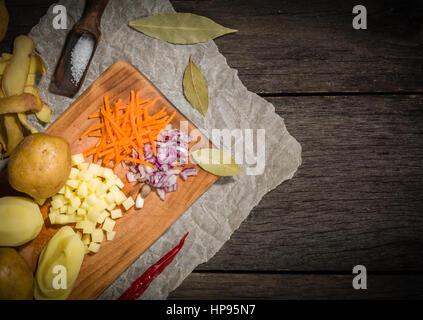 Ingredienti per la zuppa di verdure. verdure cetriolo cipolle Carote Patate piselli spezie nella sezione sul grigio Sfondo di legno Foto Stock