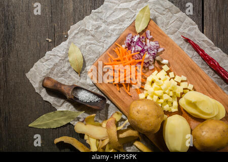 Ingredienti per la zuppa di verdure. verdure cetriolo cipolle Carote Patate piselli spezie nella sezione sul grigio Sfondo di legno Foto Stock