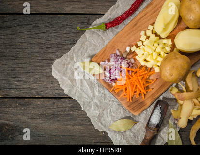 Ingredienti per la zuppa di verdure. verdure cetriolo cipolle Carote Patate piselli spezie nella sezione sul grigio Sfondo di legno Foto Stock