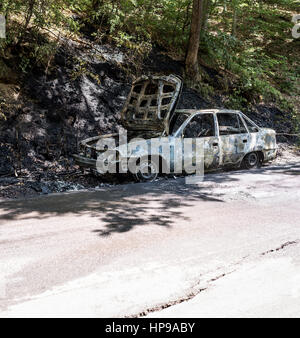 Bruciata auto rottamata dopo un incendio nella strada forestale. Bruciato auto abbandonate. Foto Stock