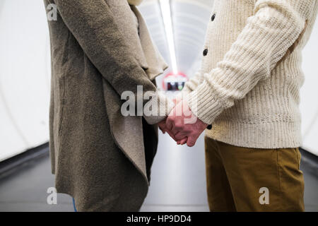 Irriconoscibile coppia senior nel corridoio della metropolitana tenendo le mani Foto Stock