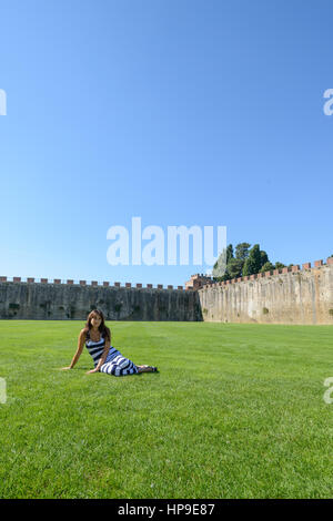 Una bella ragazza in posa sul prato di piazza dei Miracoli a Pisa Foto Stock