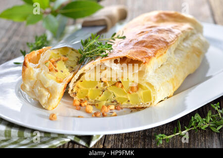 Sostanziosa cucina austriaca: strudel di patate con uova e ciccioli, servita su una tavola di legno Foto Stock