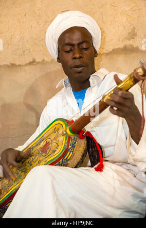 Merzouga, Marocco. Gnaoua musicista che gioca la sua Gimbrie o Hajouj. Foto Stock