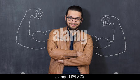 Giovane uomo contro lo sfondo di muscoli raffigurato sulla lavagna Foto Stock