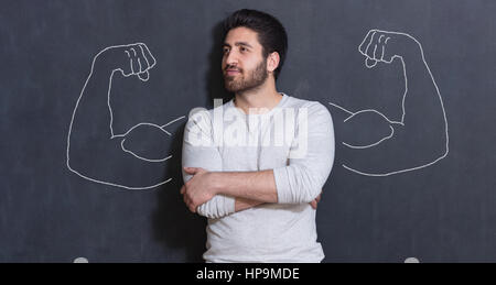 Giovane uomo contro lo sfondo di muscoli raffigurato sulla lavagna Foto Stock