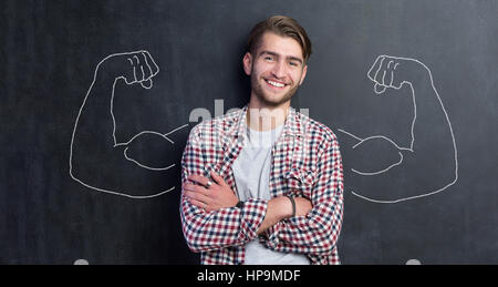 Giovane uomo contro lo sfondo di muscoli raffigurato sulla lavagna Foto Stock