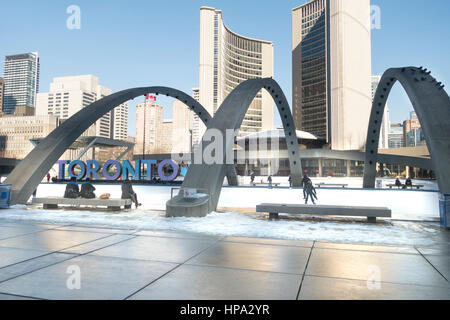 La gente di pattinaggio a Nathan Phillips Square a City Hall di Toronto, Ontario, Canada con Toronto segno tra gli archi Foto Stock