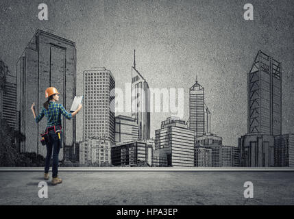 Vista posteriore di ingegnere di donna con la cartella e schizzi di progetto di costruzione sulla parete Foto Stock