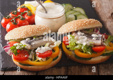 Gustoso panino con le aringhe, il sugo di pomodoro e verdure su una tabella di close-up orizzontale. Foto Stock