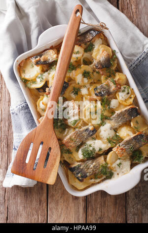 Casseruola di patate, aringhe in salsa alla panna close-up in una teglia. vista verticale da sopra Foto Stock