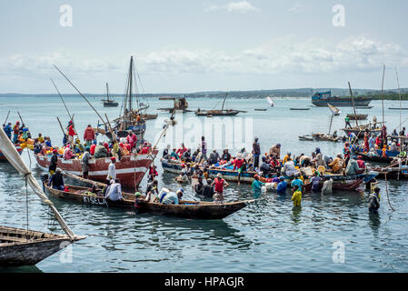 I pescatori portano il pesce per il mercato al vecchio porto Dhow per gli operatori i quali acquistano il pesce per rivenderlo nel mercato di Stone Town. La città di Zanzibar, Zanzibar, Tanzania. Foto Stock