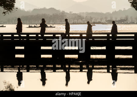 Cinque turisti in silhouette attraversare un ponte a hangzhou west lake scenic area Foto Stock