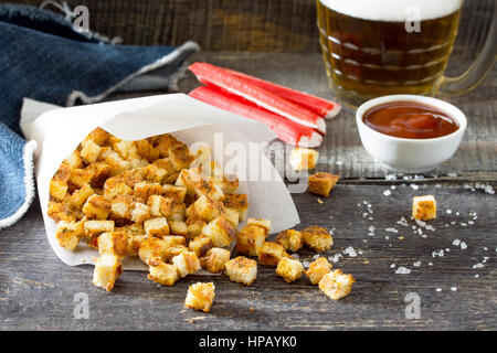 Gli snack. Crackers di granchio, essiccato il pane bianco e i bastoncini di granchio e il ketchup sul tavolo di legno. Foto Stock