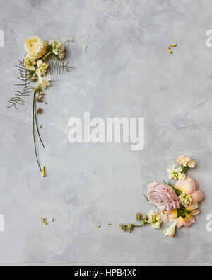 Angoli di fiori con rose e petali di fiori sul cemento grigio sfondo Foto Stock