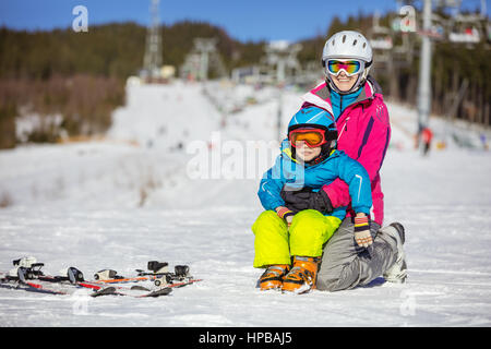 Allegro madre e figlio in appoggio sulle piste da sci e seggiovie in background Foto Stock