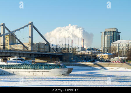 Mosca, Russia - 8 Gennaio 2017: il piacere in barca a vela su un fiume congelato sotto il ponte di strutture metalliche, gelido inverno pieno di sole giorno sullo sfondo Foto Stock