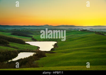 Toscana, Crete Senesi Paesaggio vicino Siena, Italia, Europa. Piccolo lago verde e i campi gialli, cielo blu con nuvole. Foto Stock