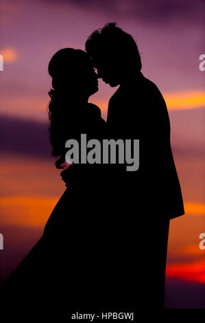 Silhouette di abbracciare Asian sposa e lo Sposo al tramonto Foto Stock