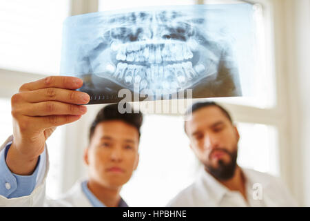 I medici guardando ad immagine a raggi x e analizzare la chirurgia orale diagnosticare Foto Stock