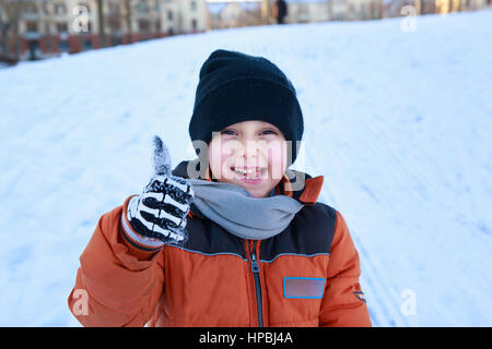 Bambino ragazzo dando Thumbs up, giocare e ridere sul nevoso inverno a piedi nella natura. Foto Stock