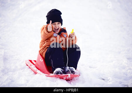 Bambino ragazzo dando Thumbs up, giocare e ridere sul nevoso inverno a piedi nella natura. Il gelo invernale. Foto Stock