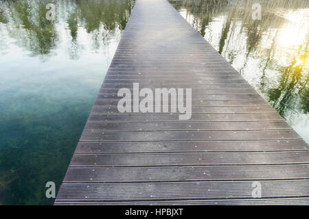 Infinito lungo il ponte pedonale su un lago con riflessioni Foto Stock