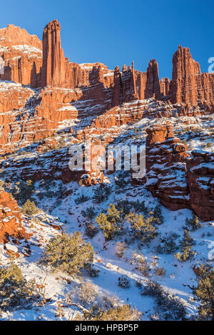 Alette di roccia si elevano al di sopra di un canyon nevoso al Fisher Towers formazioni rocciose nei pressi di Moab, Utah. Foto Stock