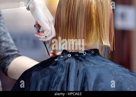 Parrucchiere rifilatura capelli biondi con le forbici Foto Stock