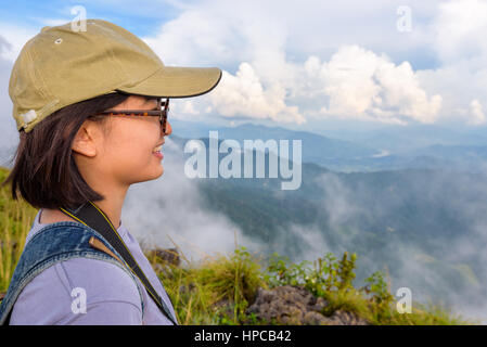 Escursionista asian teens carina ragazza con tappi e bicchieri sorridente felicemente mentre guardando bella natura di paesaggio delle montagne e del cielo durante il tramonto Foto Stock