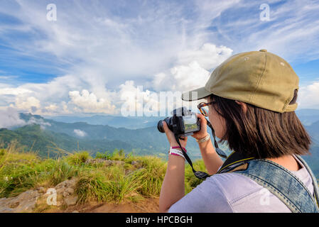 Escursionista asian teens ragazza con zaino cercando foto sulla fotocamera digitale è un bellissimo paesaggio naturale della sierra e cielo durante il tramonto sulla montagna Foto Stock