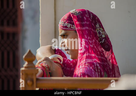 RAJASTHAN, India - 20 novembre 2016: Non identificato donna Rajasthani in attesa di qualcuno che indossa coloratissimi sari rosso Foto Stock