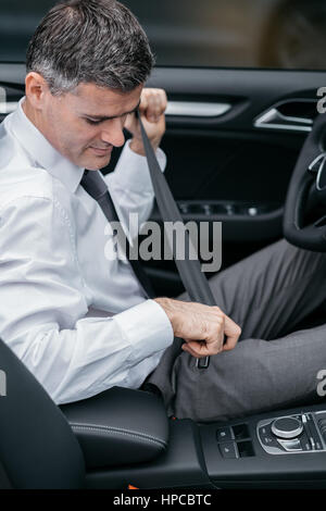 Imprenditore della sua vettura il fissaggio della cintura di sicurezza, guida sicura di concetto Foto Stock