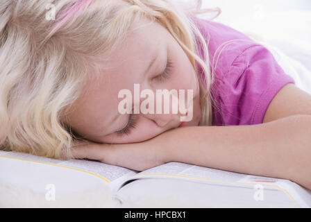 Maedchen, 7, schlaeft auf einem aufgeschlagenem Buch - ragazza dorme su un libro aperto Foto Stock