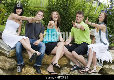 Junge Motivierte Leute, 20+, sitzen auf einer Steinmauer - i giovani su una parete Foto Stock