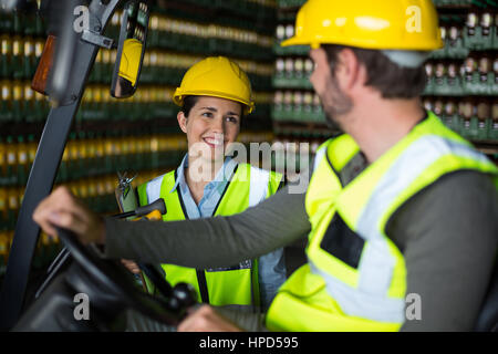 Sorridente lavoratori in fabbrica interagire gli uni con gli altri in fabbrica Foto Stock