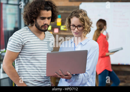 I dirigenti aziendali a discutere su computer portatile in ufficio Foto Stock