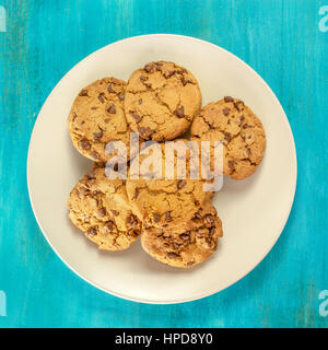 Una foto quadrata di una piastra di pane appena sfornato, scaglie di cioccolato i cookies, ripresa dall'alto su una vivace sfondo blu con copyspace Foto Stock